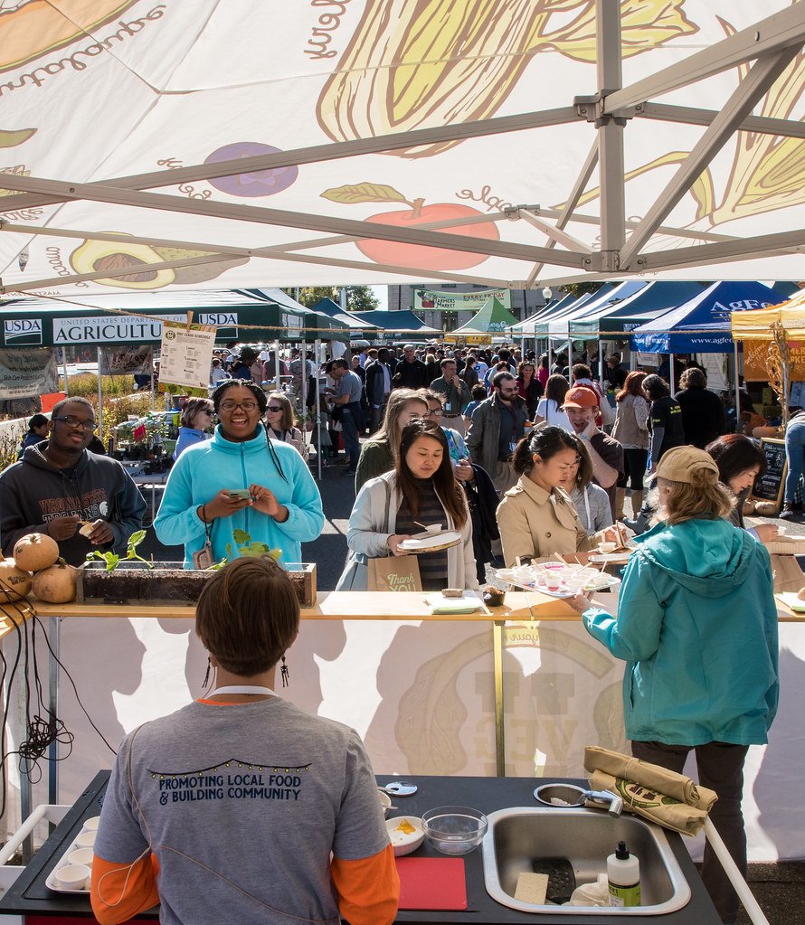Feria de productores y comercios de barrio con público recorriendo los puestos